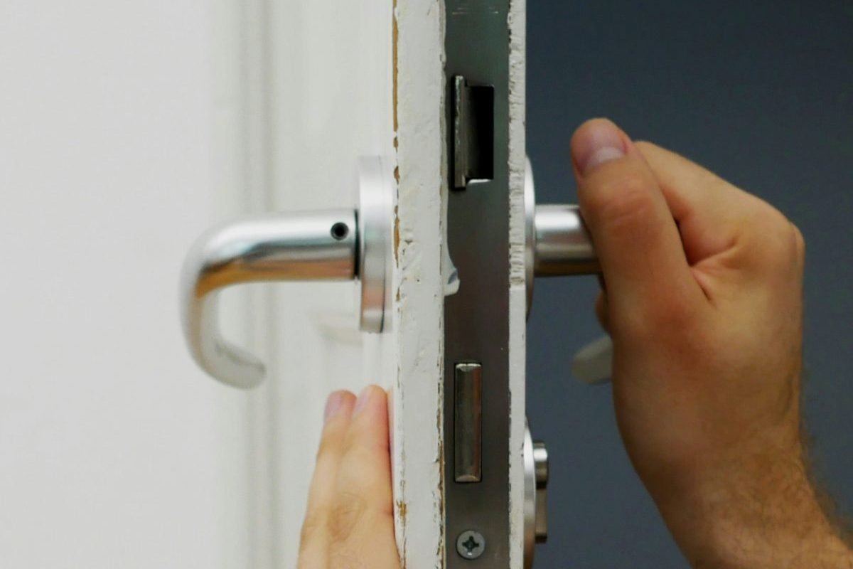 A technician fitting a mortise lock into the edge of a white door