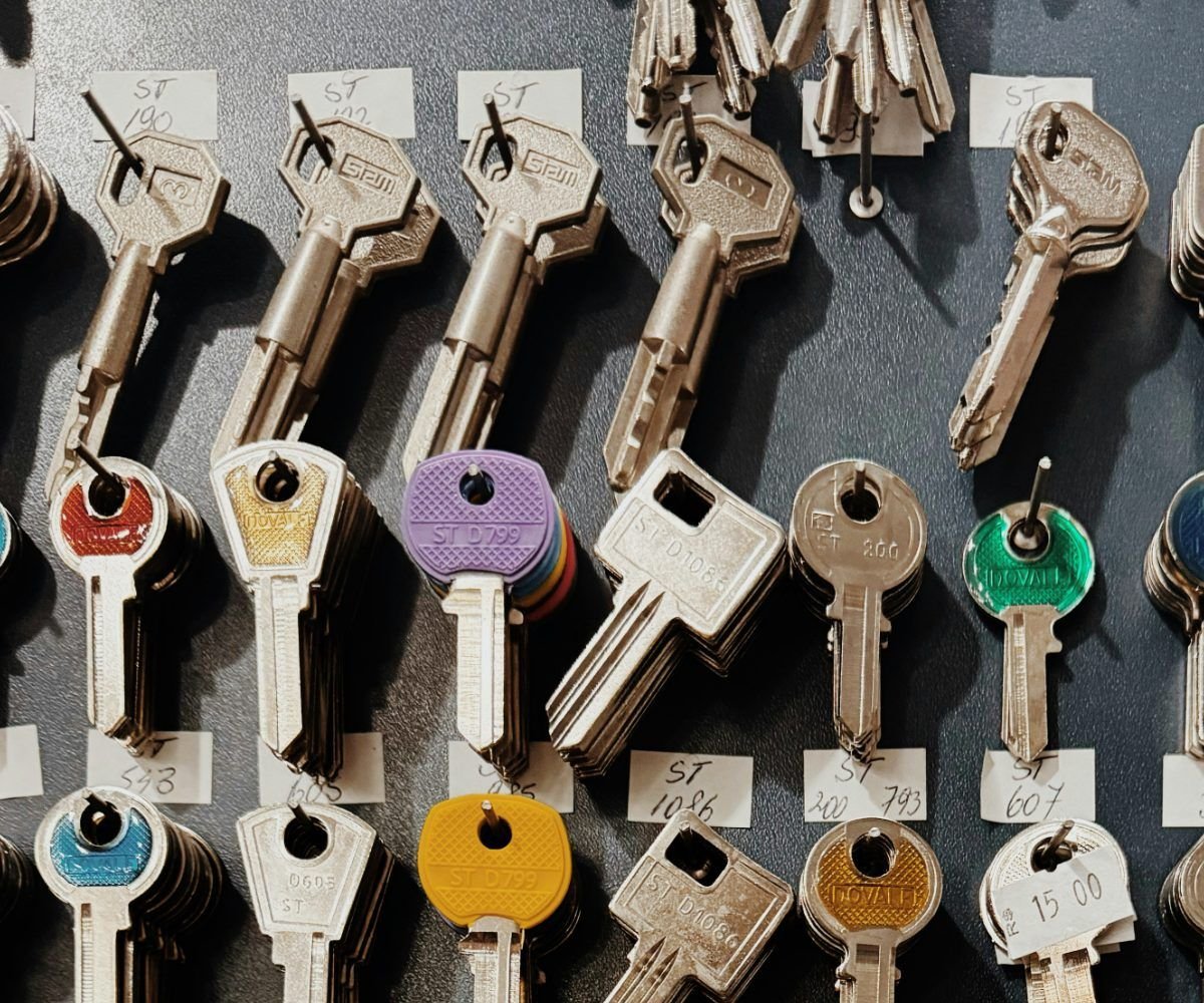 Rows of key blanks with coloured plastic heads hanging on a labelled display board